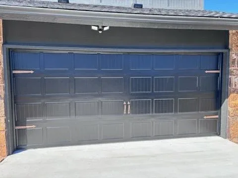 Dark raised panel garage door with decorative hardware installed in OKC by Affordable Door Co